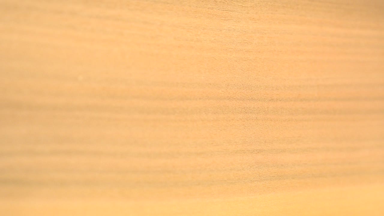 Yellow-orange wood grain fills the first frame of the Westminster, Colorado abstract clip, with no visible people.