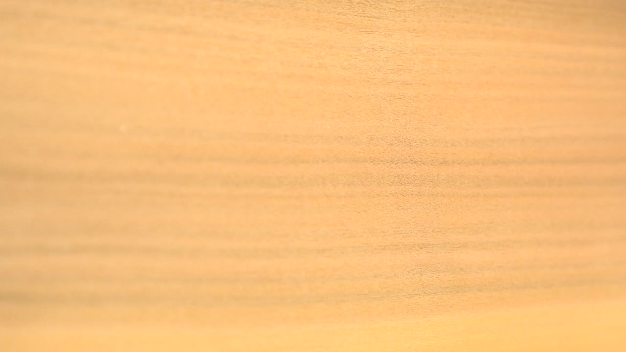 A closer orange-yellow wood surface appears in Westminster, Colorado footage, with darker horizontal grain and no visible people.