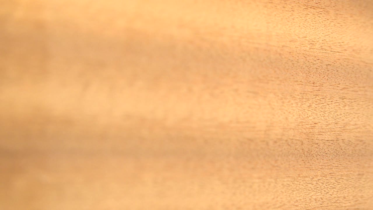 Close tan wood grain fills the frame with soft warm light.
