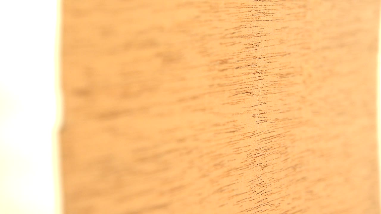 Close yellow wood surface with dark grain lines and a bright side edge.