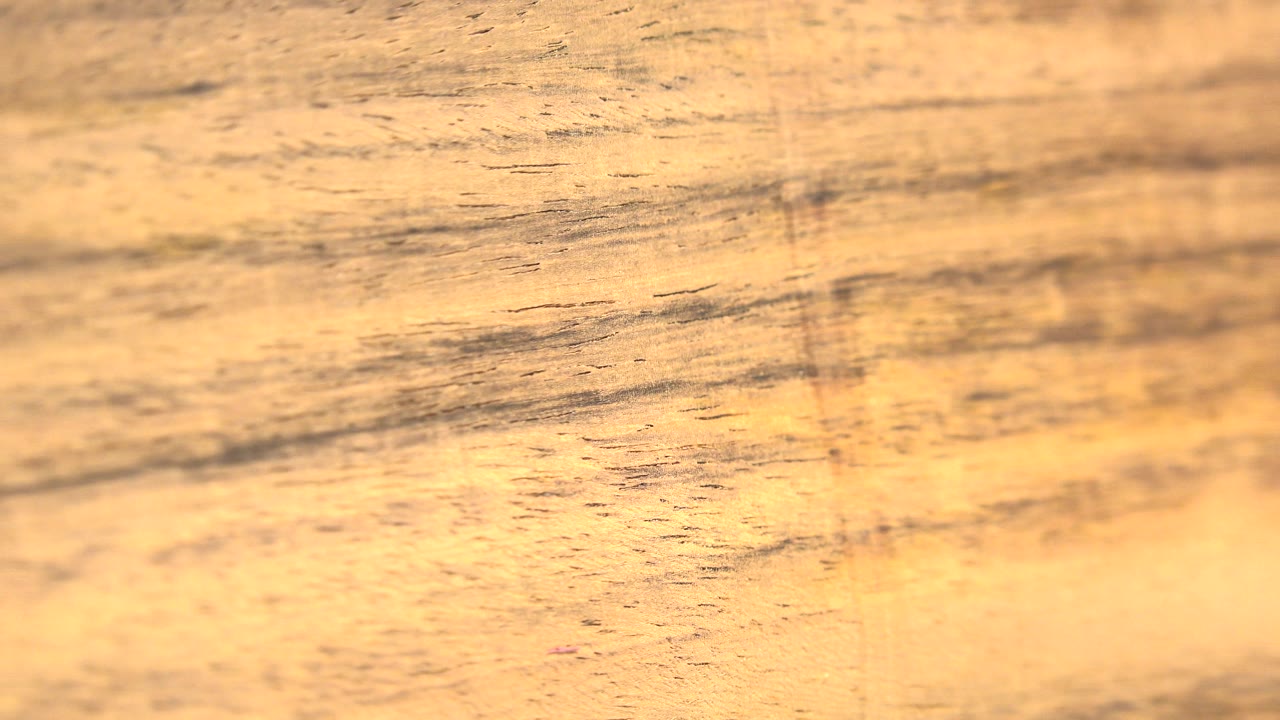 Warm wood-like surface with dark grain streaks and a faint vertical mark.