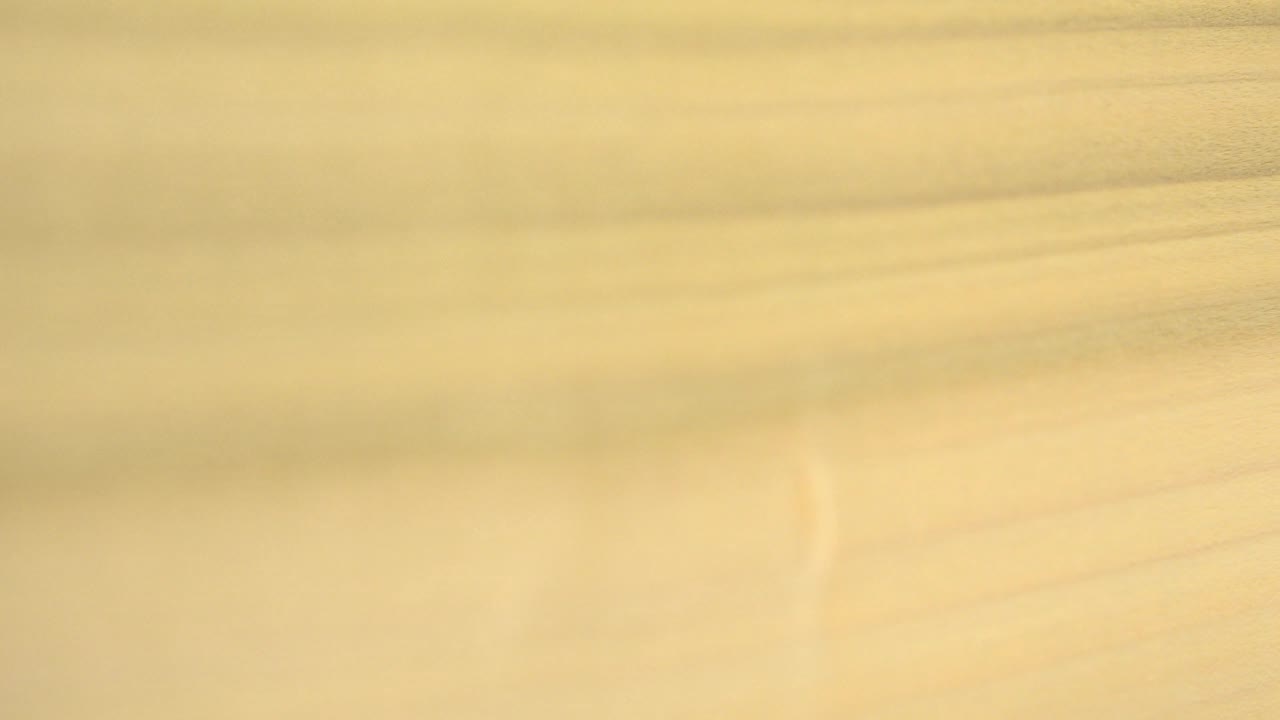 A close view of the Westminster, Colorado texture shows pale gold light, faint curved marks, soft brown bands, and no visible people.
