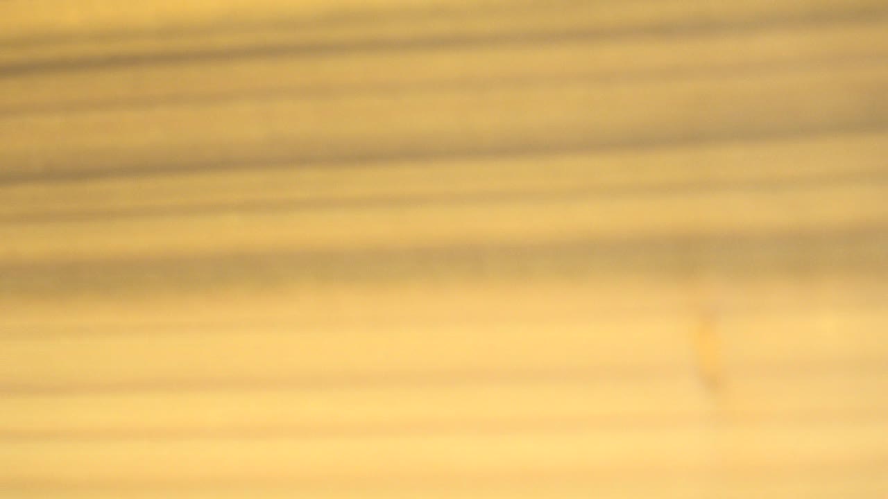 At 0:00, a soft close-up of tan wood grain fills the Westminster, Colorado clip frame, with plank lines running across the image and no visible people.