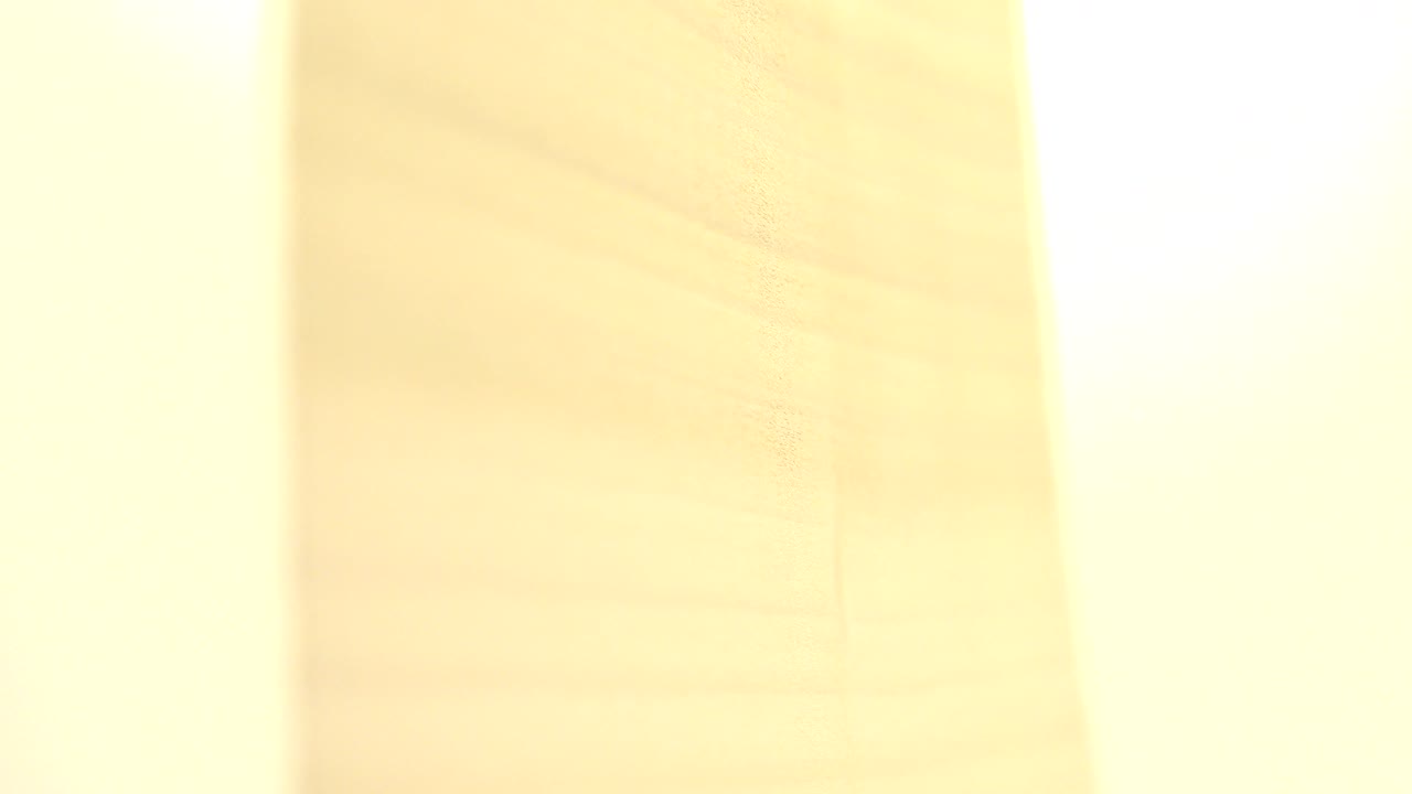 At 0:00, a bright yellow rectangular plate or sheet fills the close frame against a pale wood-grain surface in Westminster, Colorado, with no visible people.