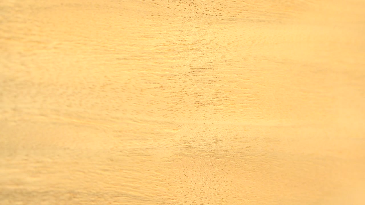 Bright close-up of the rotating tan board in Westminster, Colorado, with subtle darker grain bands and no visible people.