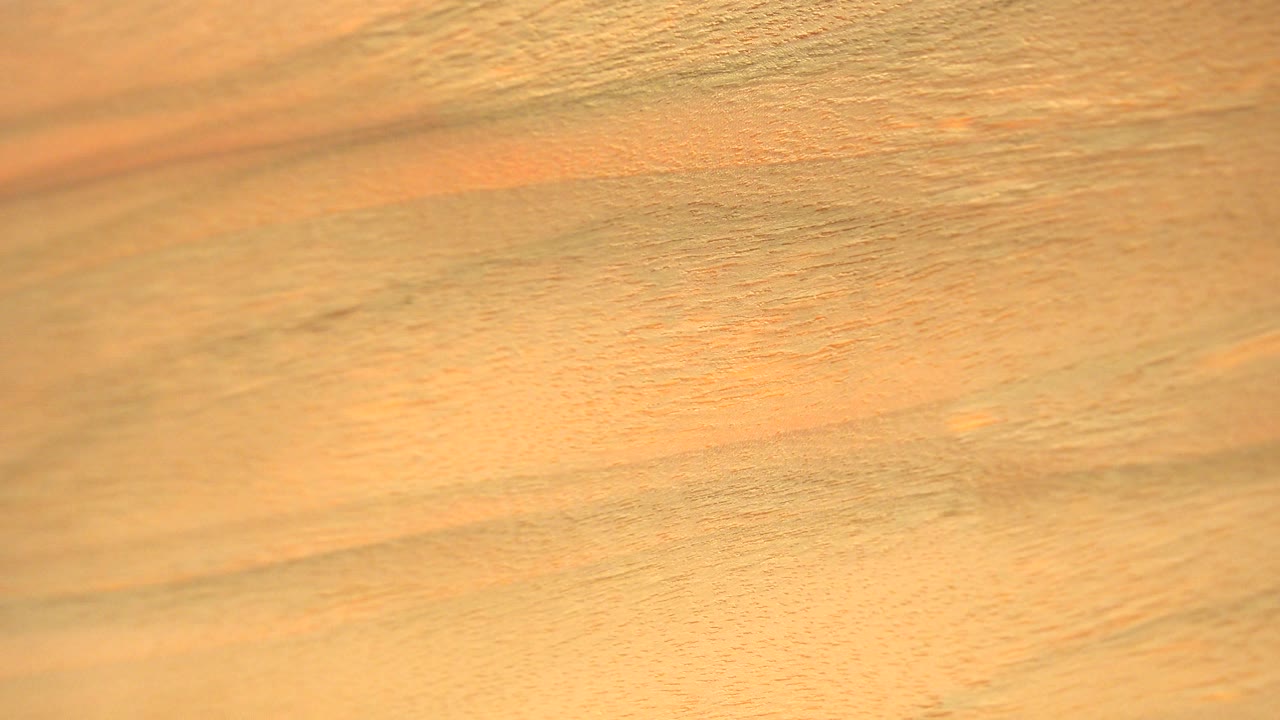 Close view of a golden orange lamina-like surface in Westminster, Colorado, with soft grain, darker streaks, and no visible people.
