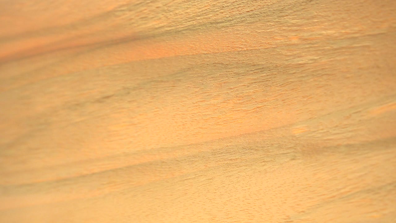 A close material texture shows a blown-out white band and pale yellow edge beside the warm surface, with no visible people.