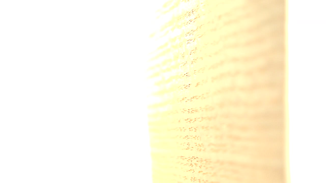 Soft-focus close-up of the rotating tan paper surface with a wide overexposed white strip in Westminster, Colorado, with no visible people.