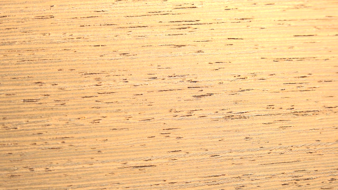 Close-up of a light tan fibrous surface with scattered dark brown grain marks in Westminster, Colorado, with no visible people.