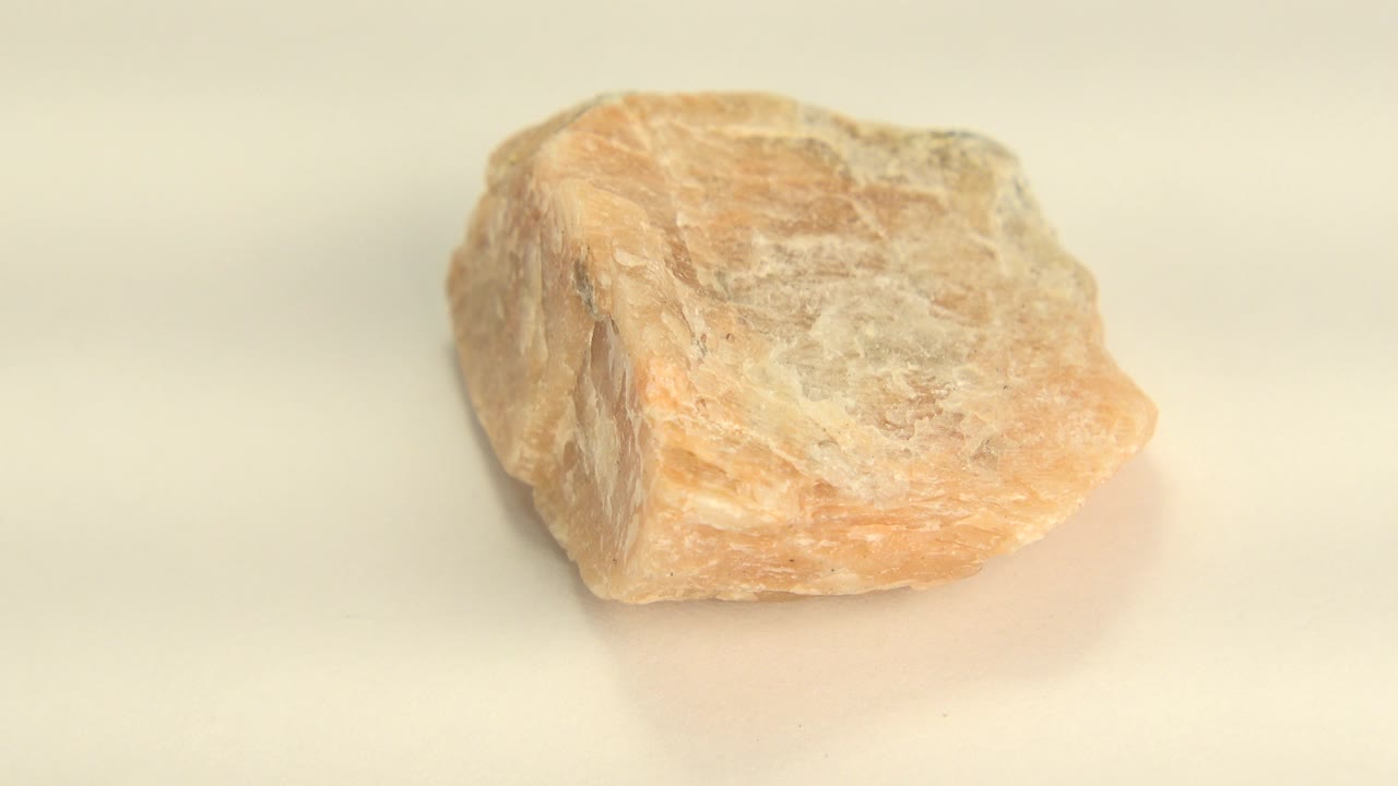 Close-up of the yellow sandstone rock on a light tabletop in Westminster, Colorado footage, with a squared side and textured top visible and no visible people.