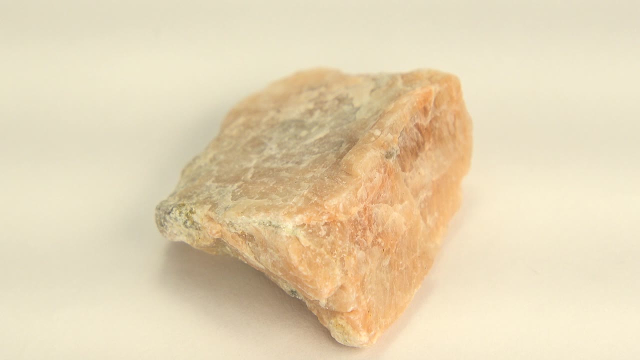 Close-up of a pale yellow and orange quartz sandstone rock on a cream background in Westminster, Colorado, with no visible people.