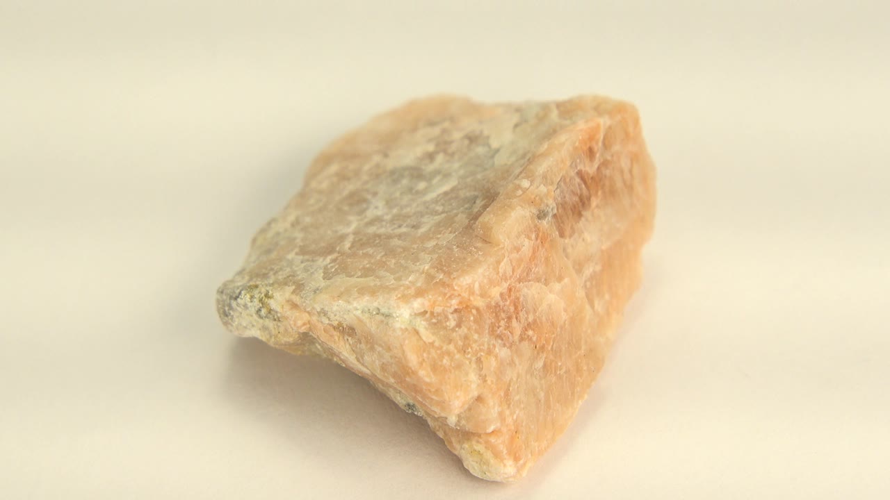 The quartz sandstone remains centered on the plain cream surface, showing a broad chalky top plane and orange side in Westminster, Colorado, with no visible people.