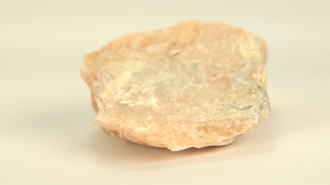 Pink-white rock turned slightly on a plain floor.