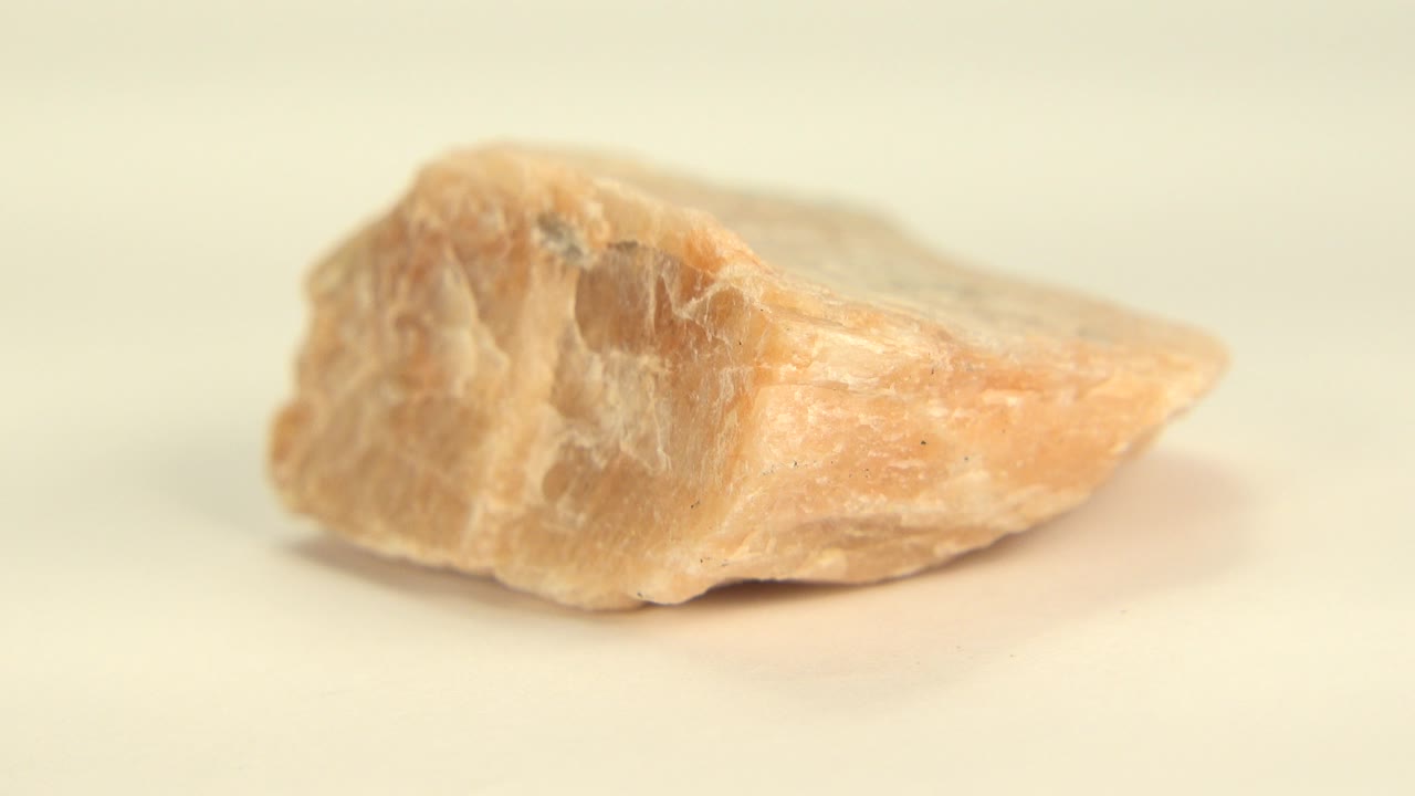 Close-up of a yellow-orange sandstone quartz rock lying low on a pale surface in Westminster, Colorado, with soft light and no visible people.