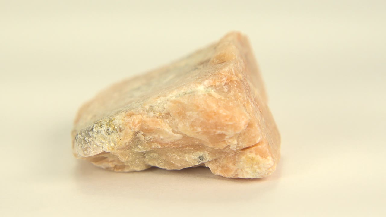 Pale yellow crystal on a beige surface in close-up.