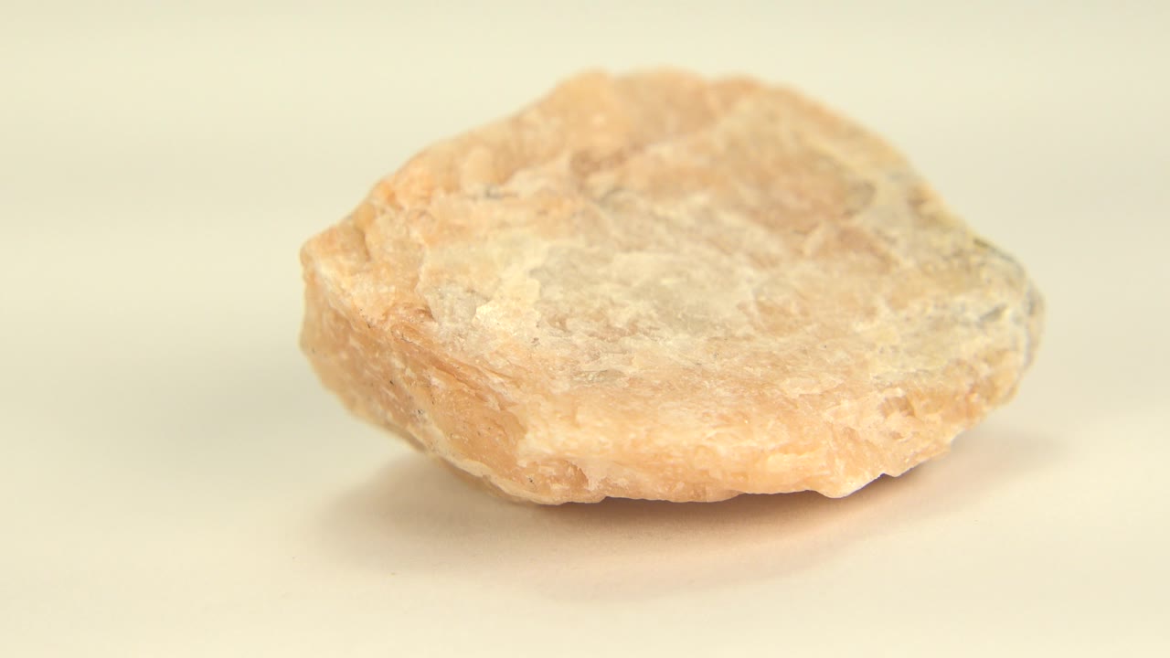 At 0:00, a tan brown rock sits centered on a cream surface in Westminster, Colorado, with a soft shadow underneath and no visible people.