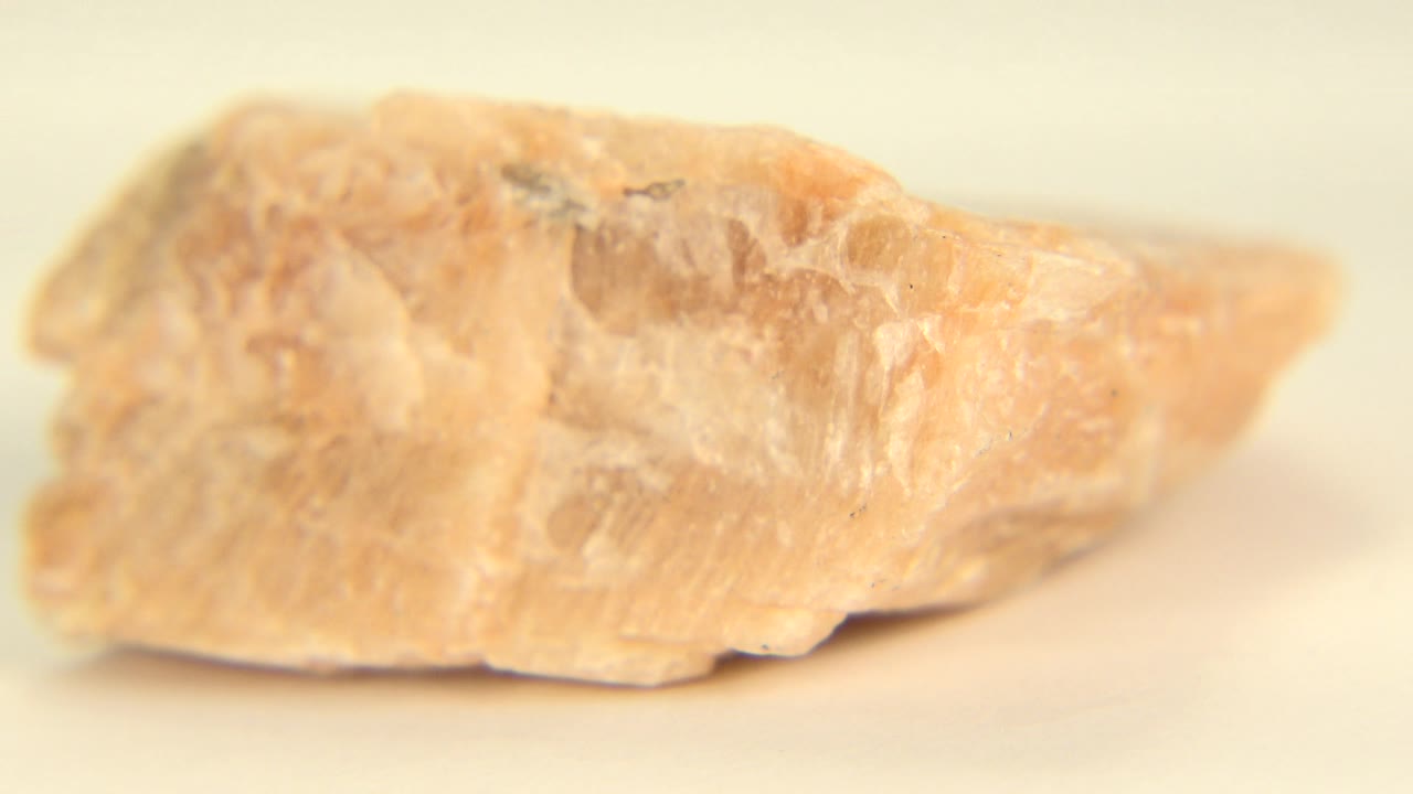 Peach rock with a bright side edge against pale sand.