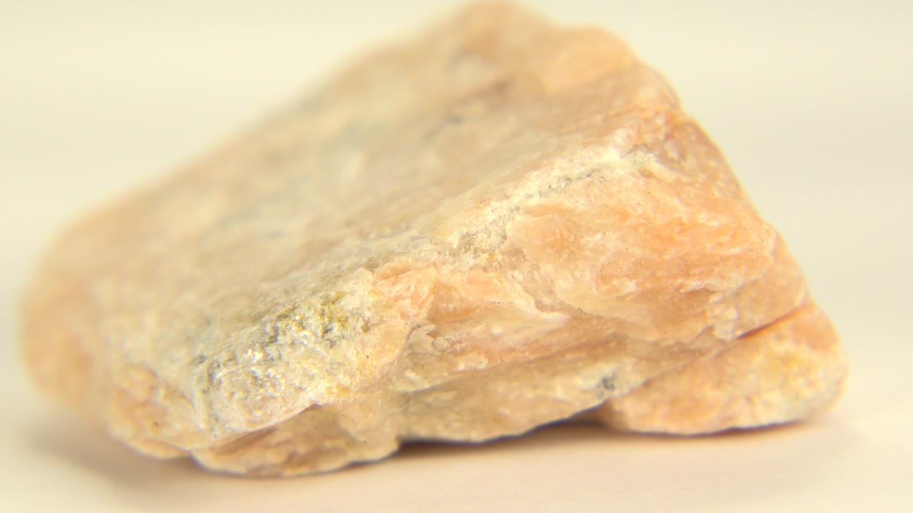 Close view of a tan stone angled across a pale background.