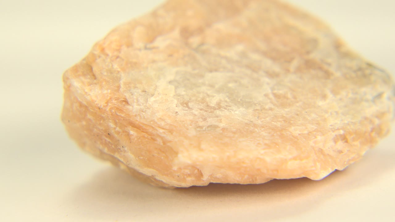 A peach-orange crystal rock sits low on a pale cream surface in Westminster, Colorado, with soft focus and no visible people.