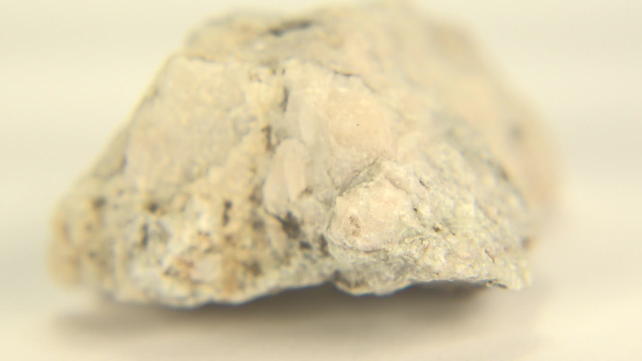 A pale deformed rock sits low in frame on a white surface in Westminster, Colorado, with soft focus at the rear and no visible people.