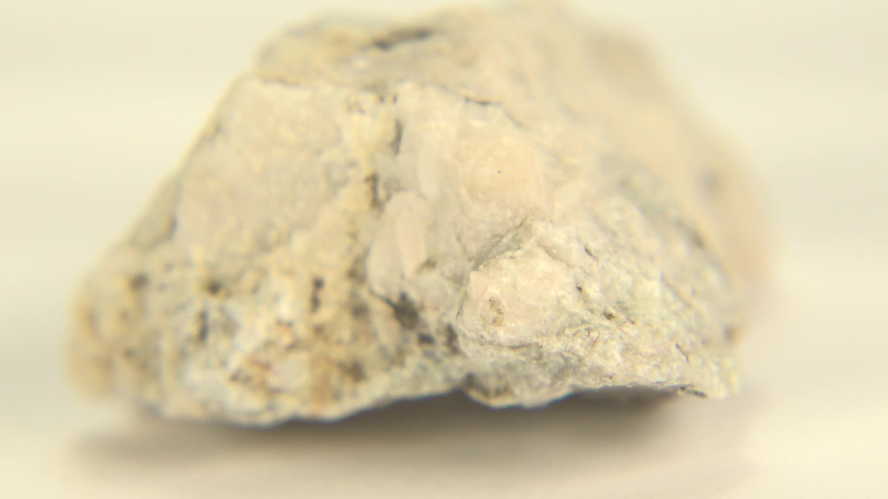 The rock remains centered on a warm white background in Westminster, Colorado, with rough gray speckling and no visible people.
