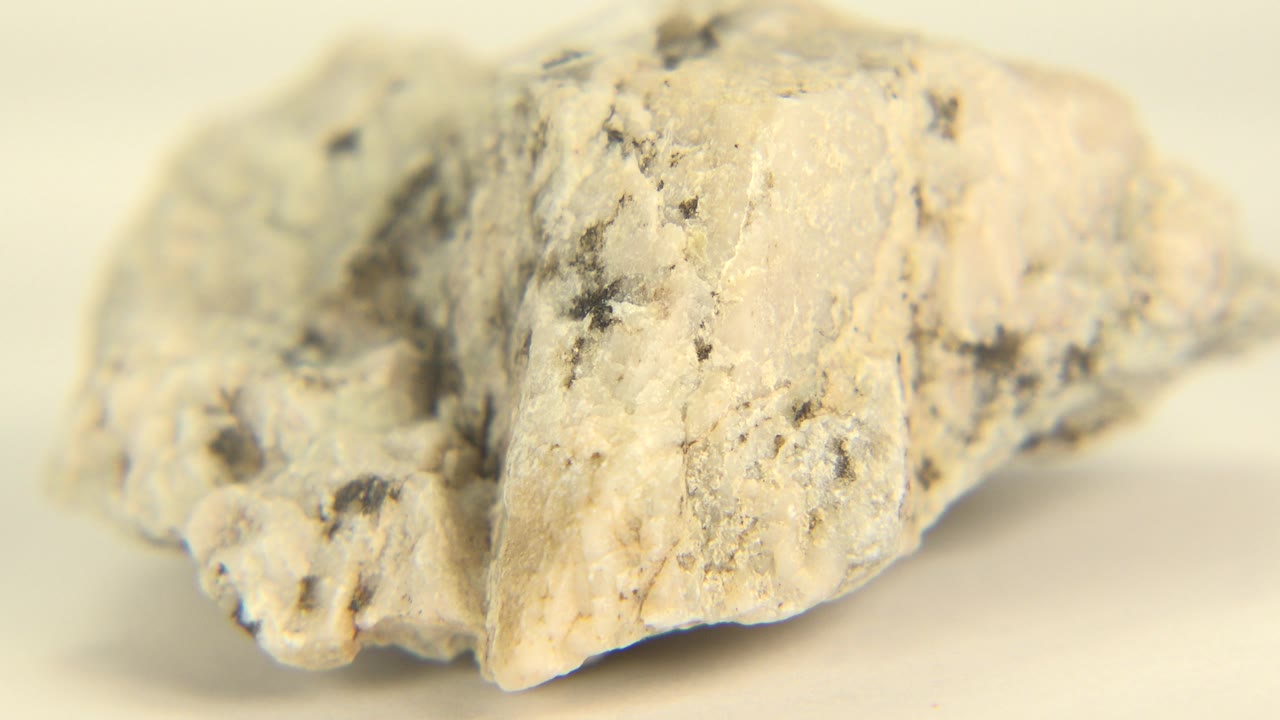 Close quartz rock with a brighter right edge and dark speckles.