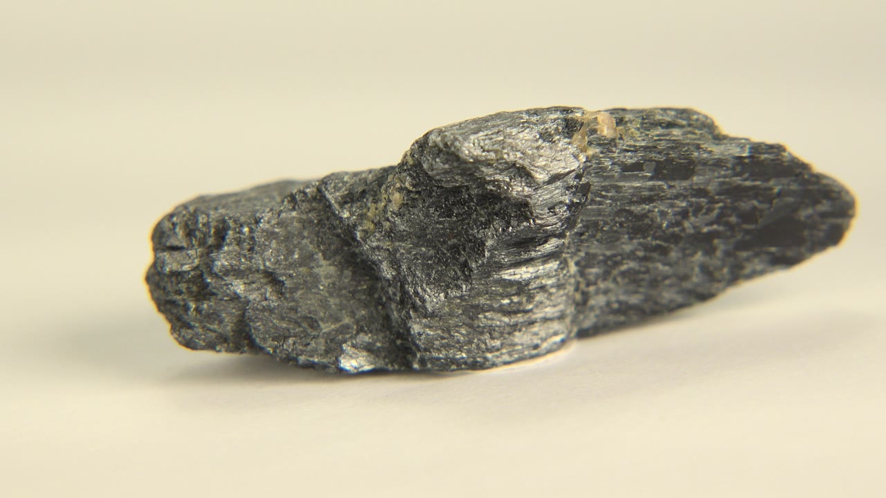 Dark gray rough stone seen from the side on a pale flat surface in Westminster, Colorado, with soft background blur and no visible people.