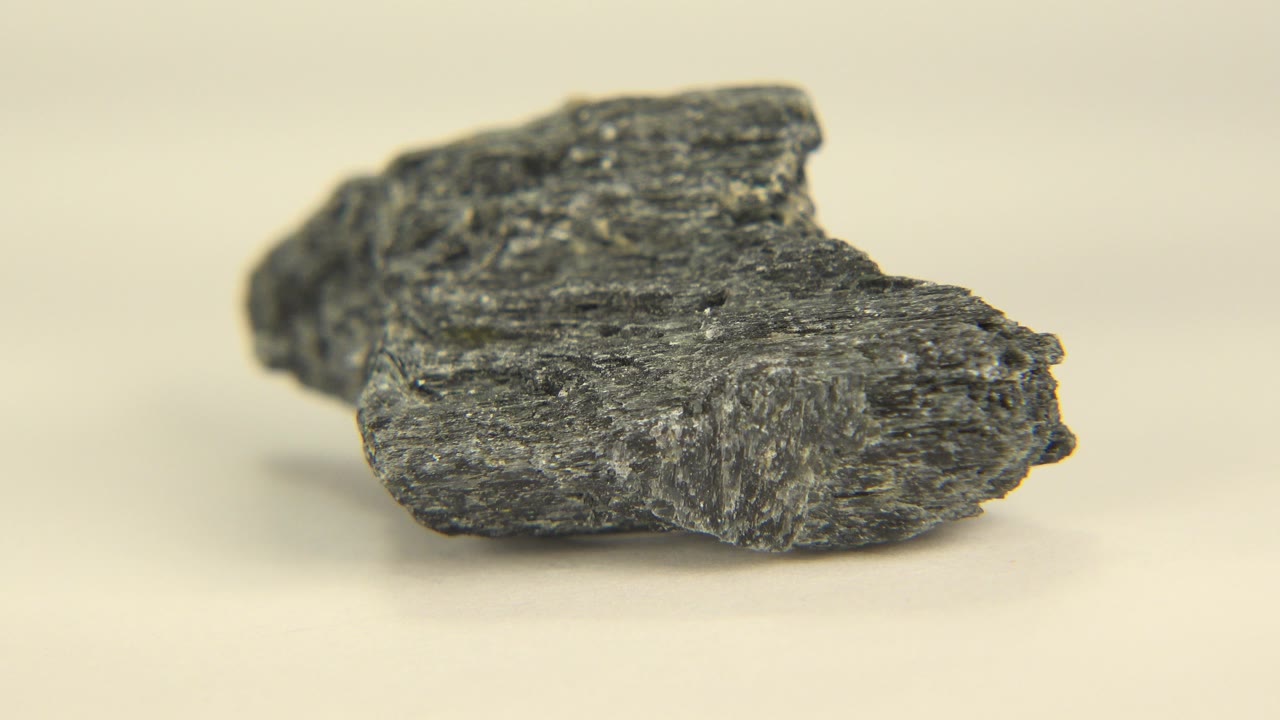 Dark gray stone seen very close on a warm cream surface in Westminster, Colorado, with shallow focus and no visible people.