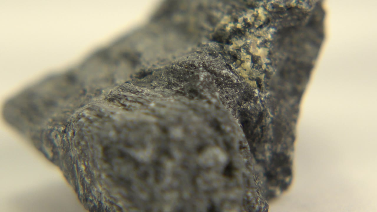 At the start of the Westminster, Colorado clip, a rough black rock sits in tight shallow focus on a white surface with no visible people.
