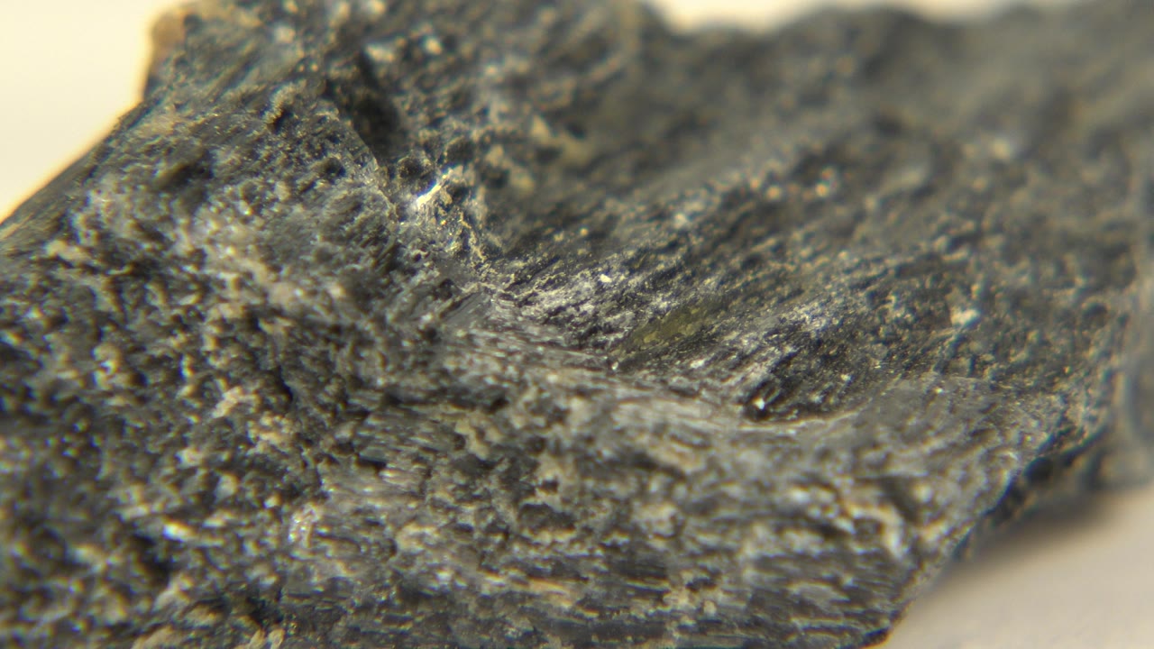 Close-up of a dark gray mineral fragment with rough ridges and shallow focus in Westminster, Colorado, with no visible people.