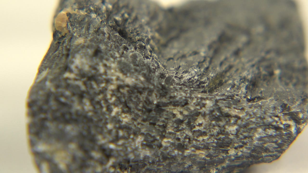 Close view of a mineral edge with a small tan deposit near the top.