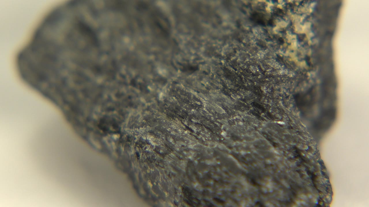 The rock remains close to the lens in Westminster, Colorado footage, showing a rough central face, soft pale background, and no visible people.