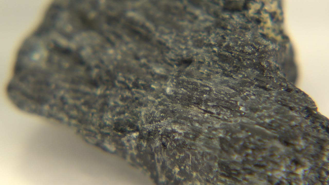 Dark stone object angled across a warm pale surface.