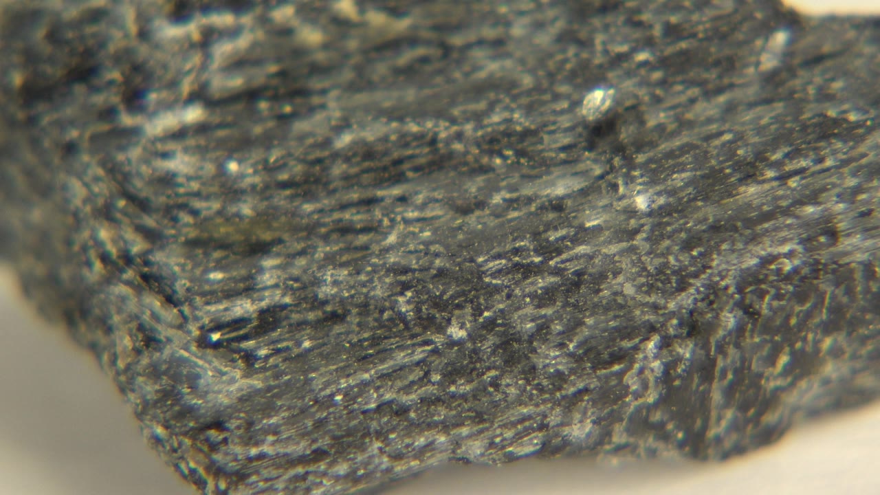 Rough black object edge shown in close detail on a white floor.