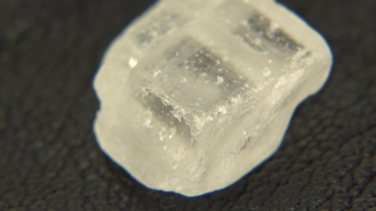 Clear quartz rock seen close up on a dark textured surface in the Westminster, Colorado 2015 clip, with a bright milky edge and no visible people.