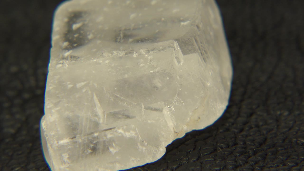 At 0:00, a murky white quartz specimen sits close to the lens on a black textured surface in Westminster, Colorado, with no visible people.