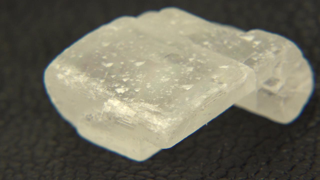 Translucent white quartz crystal on a black textured surface.