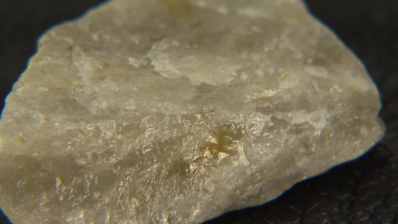 A pale white rock fills the frame on a dark surface in Westminster, Colorado, with chipped translucent edges and no visible people.
