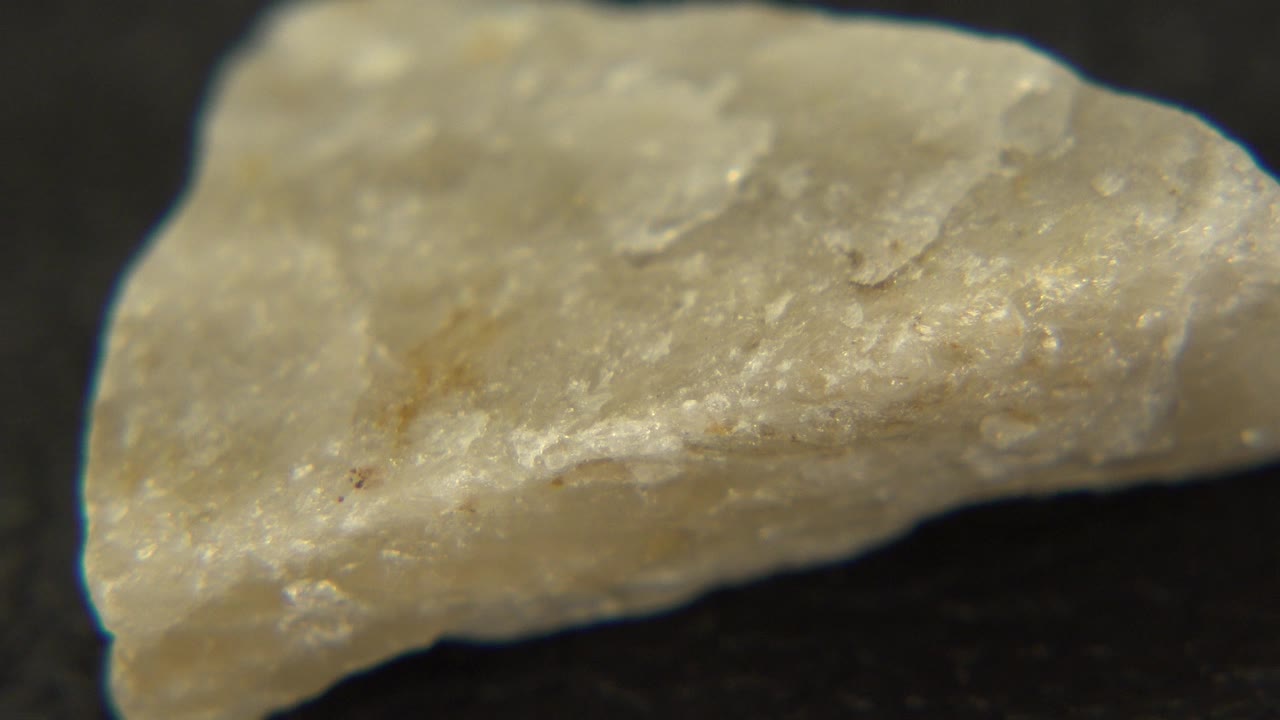 Pale yellow quartz-like stone seen close up on a black surface in Westminster, Colorado, with rough edges and no visible people.