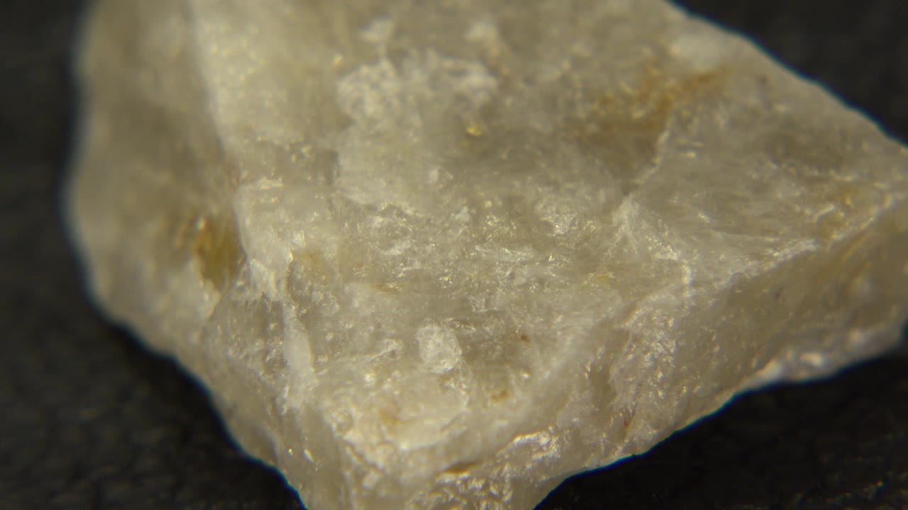 Close-up of a pale rough stone with cloudy translucent texture on a dark surface in Westminster, Colorado, with no visible people.