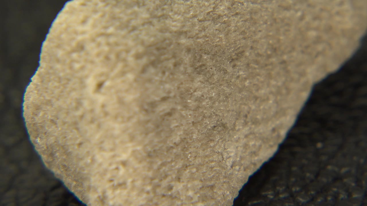 The yellow stone appears turned from the previous moment, with a brighter upper edge and dark out-of-focus background in Westminster, Colorado, with no visible people.