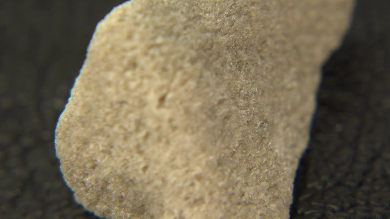 Rough yellow stone close-up with a rounded edge in focus.