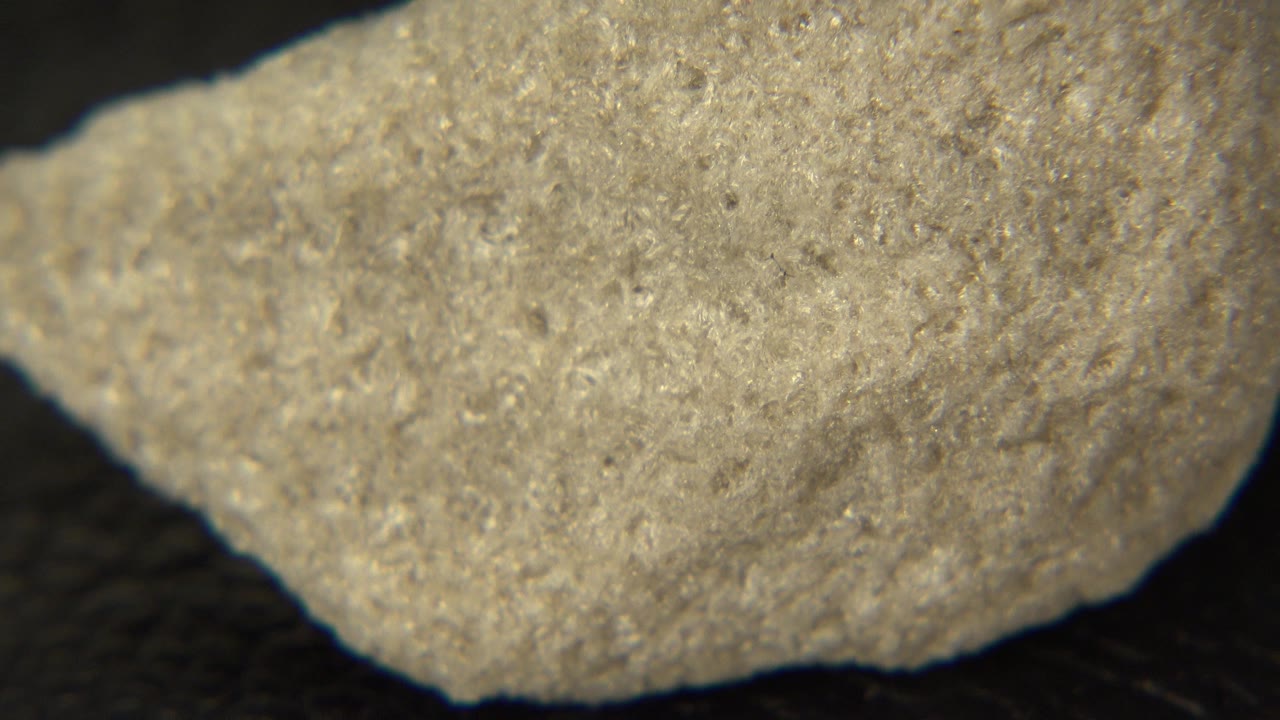 The rock remains in extreme close-up in Westminster, Colorado footage, with a broad pale face and darker shadowed background below, and no visible people.