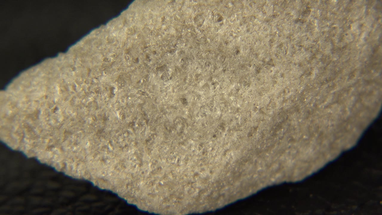 Light gray rock angled across a dark background.