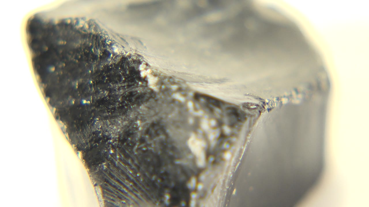 At 0:00 in Westminster, Colorado, a dark translucent rock edge fills the frame against a warm white background, with no visible people.