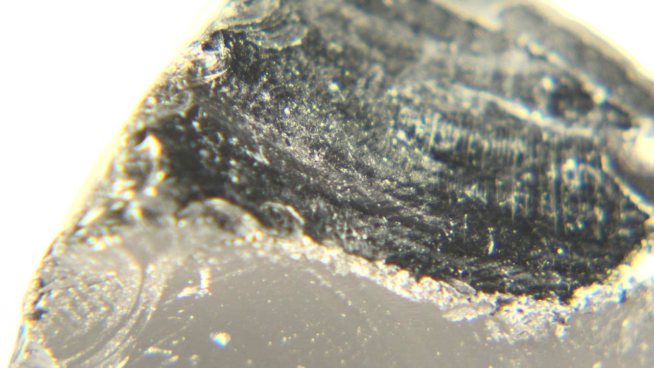 Macro view of a translucent rock with a dark shiny face.