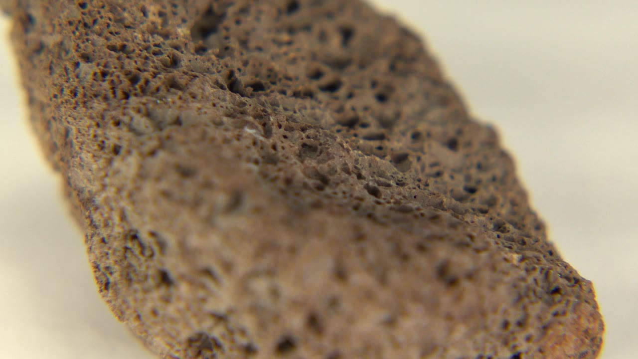 Macro detail of a brown rock with a darker porous top edge