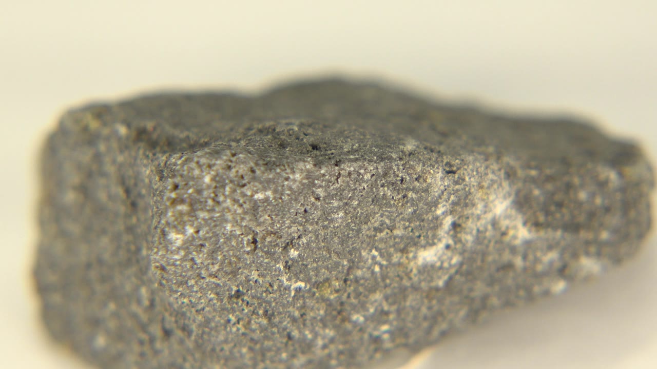 The rock remains centered in Westminster, Colorado, with a flatter front face, white flecks, small dark pits, and no visible people.