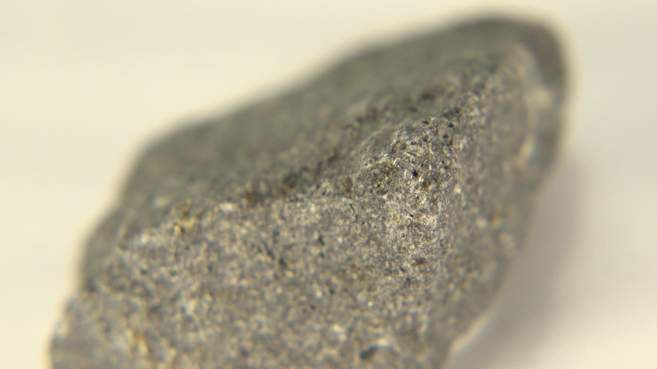 Close view of a gray rock on a white surface.