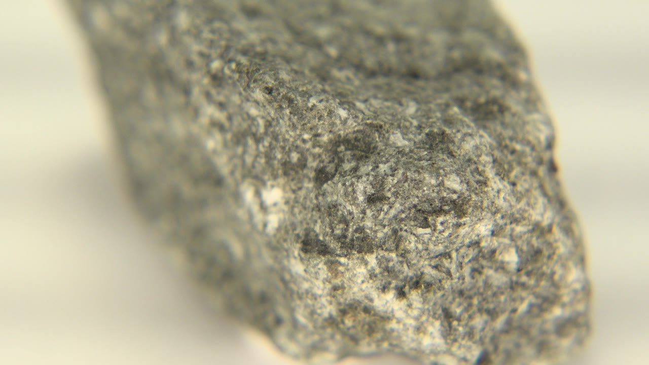 Close-up of a gray rough stone on a pale surface.